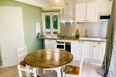 a kitchen with a wooden table and white cabinets at Gîte Studio Les Ecureuils in Narbonne