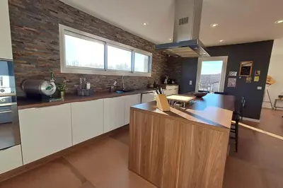 a kitchen with white cabinets and a brick wall at Villa Famara in Montredon
