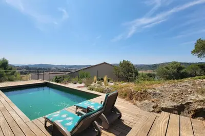 a swimming pool on a wooden deck with two chairs at Villa Famara in Montredon