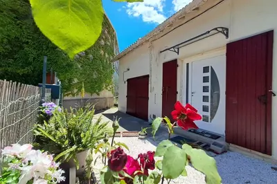 a garage with red doors and flowers in a yard at L'évasion des Corbières in Portel-des-Corbières