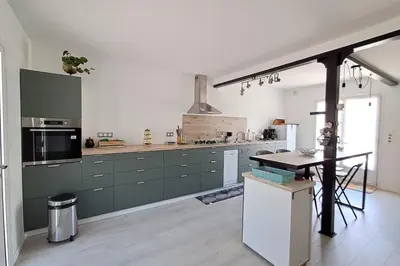 a kitchen with green cabinets and a table in it at L'évasion des Corbières in Portel-des-Corbières
