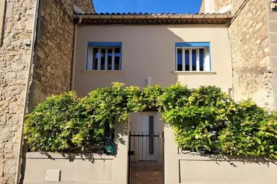 a house with a gate in front of a building at La Glycine in Portel-des-Corbières