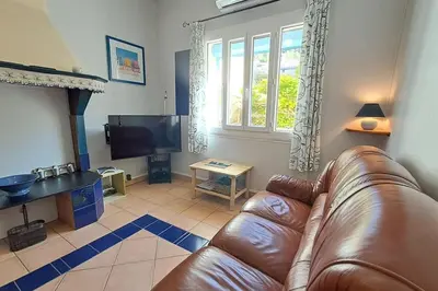 a living room with a leather couch and a television at La Glycine in Portel-des-Corbières
