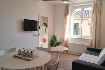 a living room with a table and a couch at L'Olympe - Appartement cosy à 2 pas des Halles in Narbonne