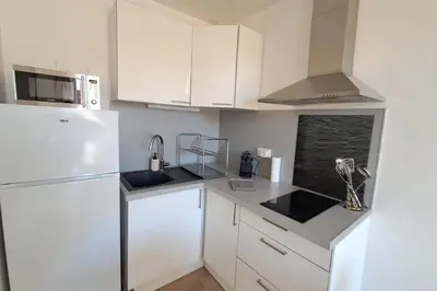 a kitchen with white cabinets and a white refrigerator at L'Olympe - Appartement cosy à 2 pas des Halles in Narbonne