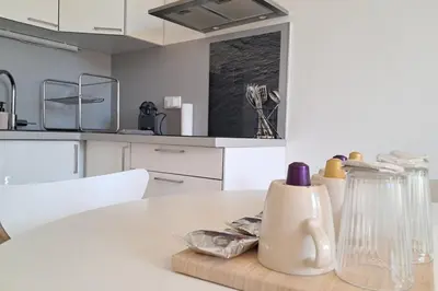 a kitchen with a white table with a vase on it at L'Olympe - Appartement cosy à 2 pas des Halles in Narbonne