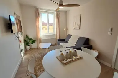 a living room with a white table and a couch at L'Olympe - Appartement cosy à 2 pas des Halles in Narbonne