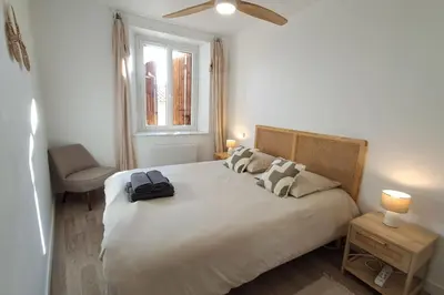 a bedroom with a large bed with a black bag on it at L'Olympe - Appartement cosy à 2 pas des Halles in Narbonne