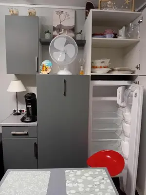 a white refrigerator with a fan and a red chair at Les maisons sur la plage in Gruissan