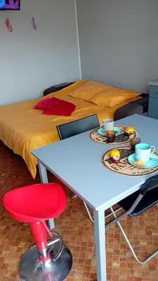 a table with two plates of food and a red stool at Les maisons sur la plage in Gruissan