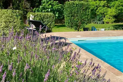 a person sitting in a chair next to a swimming pool at Gîte Studio Les Oliviers in Narbonne