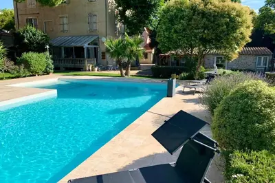 a swimming pool with chairs in front of a house at Gîte Studio Les Oliviers in Narbonne