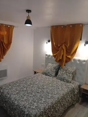 a bedroom with a bed with orange curtains at Grand logement en souplex entier in Castres