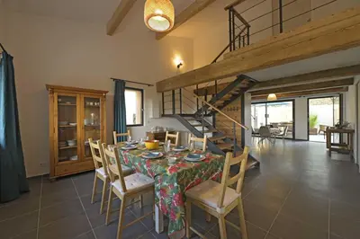 a dining room with a table and chairs and a staircase at La maison du merle bleu in Quintillan