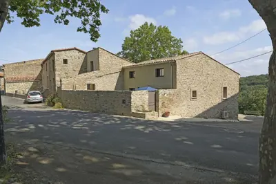 a stone house with a stone wall next to a street at La maison du merle bleu in Quintillan