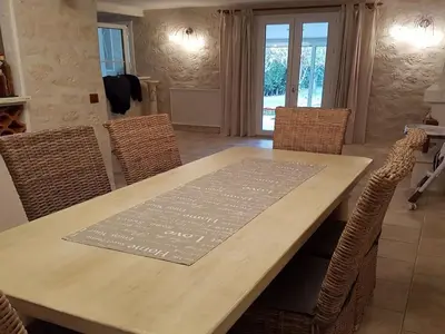 a dining room table with wicker chairs and a wooden table with a sign on at Holiday Home Charmante 3 Villa La Milouyette by Interhome in Peyriac-Minervois