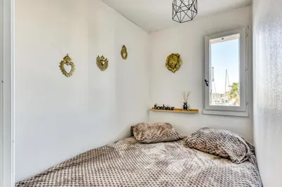 a bedroom with white walls and a bed with pillows at Studio cosy au bord du port à proximité de tout commerce in Gruissan