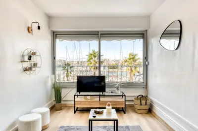 a living room with a large window and a tv at Studio cosy au bord du port à proximité de tout commerce in Gruissan