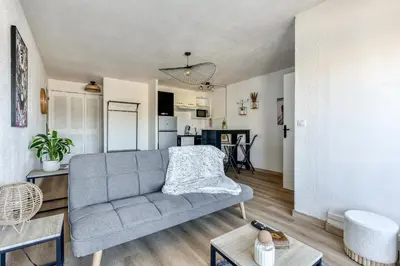 a living room with a couch and a kitchen at Studio cosy au bord du port à proximité de tout commerce in Gruissan