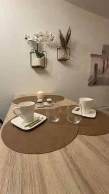 a wooden table with two cups and glasses on it at Studio cosy au bord du port à proximité de tout commerce in Gruissan