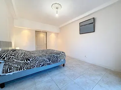a bedroom with a black and white bed and a tv at Le Mirabeau - Appartement bourgeois - Terrasse 80m2 - Wifi et Climatisation in Narbonne