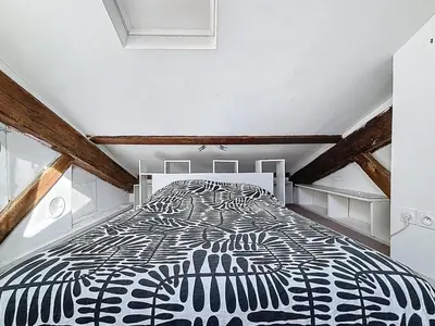 a bedroom with a black and white bed in a attic at Le Mirabeau - Appartement bourgeois - Terrasse 80m2 - Wifi et Climatisation in Narbonne