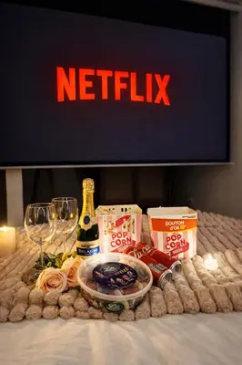 a table with wine glasses a bottle of beer and a netflix sign at Suite Bali et sauna privé - vidéo projecteur - escapade romantique-centre in Carcassonne
