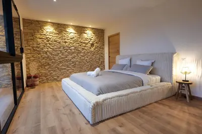 a bedroom with a white bed and a stone wall at Gîte La Choule in Mourvilles-Hautes