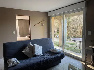 a blue couch in a living room with a sliding glass door at Gîte Au Coeur Du Pays Cathare in Fanjeaux