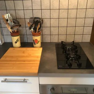 a kitchen counter with two containers of utensils and a stove at Gîte Au Coeur Du Pays Cathare in Fanjeaux