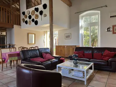 a living room with leather couches and a table at Bienvenue à l'école des garçons ! in Ouveillan