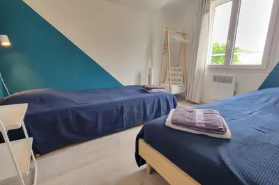 a bedroom with two beds with blue sheets and a window at Lo Cabanot maison de pêcheur pour 4 in Port-la-Nouvelle