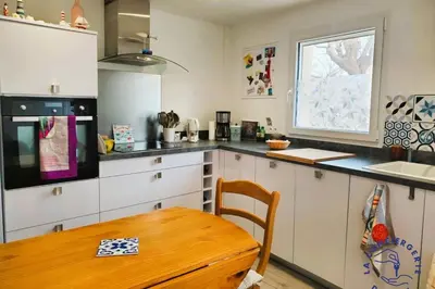 a kitchen with white cabinets and a wooden table at Lo Cabanot maison de pêcheur pour 4 in Port-la-Nouvelle