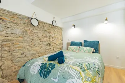 a bedroom with a bed with a stone wall at Le Gite Vegetal Cite Wifi Machine a laver 2 personnes in Carcassonne