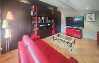 a living room with a red couch and a tv at Un Veritable Havre De Paix in Roquebrun