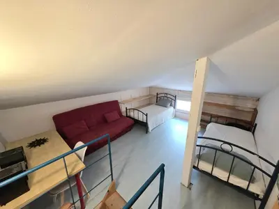 a living room with a red couch and two bunk beds at Grande maison familiale, spacieuse et confortable in Espira-de-lʼAgly