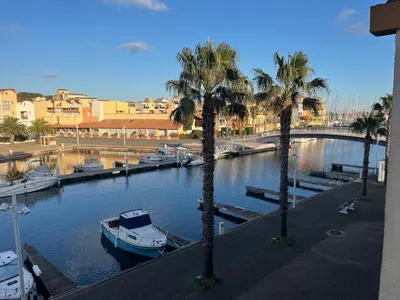 a boat is docked in a river with palm trees at Gruissan - T2 cosy 4 pers - Proche port - FR-1-796-95 in Gruissan