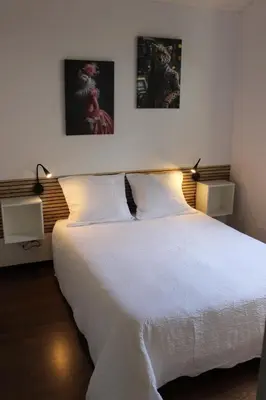 a bedroom with a white bed with two pictures on the wall at La petite maison in Cuxac-Cabardès