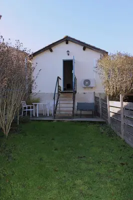 a white house with a porch and a yard at La petite maison in Cuxac-Cabardès
