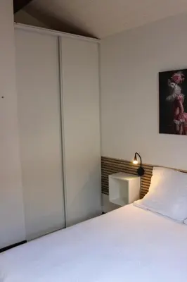 a bedroom with a white bed and a lamp at La petite maison in Cuxac-Cabardès