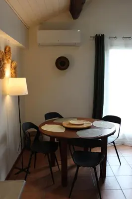 a table and chairs in a room with a lamp at La petite maison in Cuxac-Cabardès