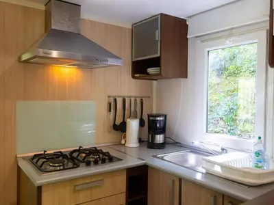 a kitchen with a stove and a sink and a window at Mobil home 6 pers avec terrasse à Fenouillet - API-1-52-314 in Fenouillet