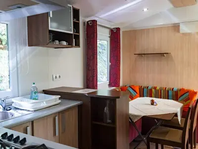 a kitchen with a counter and a table with a chair at Mobil home 6 pers avec terrasse à Fenouillet - API-1-52-314 in Fenouillet