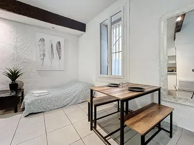 a bedroom with a bed and a table in it at Le Baudinet - Studio - Centre Ville - Rez-de-Chaussée in Narbonne