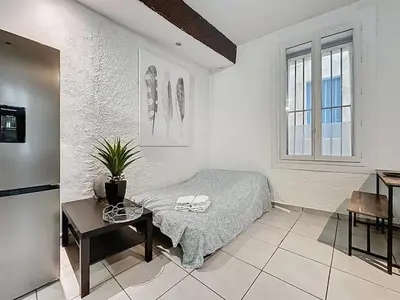 a bedroom with a bed and a table and a window at Le Baudinet - Studio - Centre Ville - Rez-de-Chaussée in Narbonne