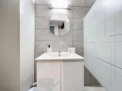 a white bathroom with a sink and a mirror at Le Baudinet - Studio - Centre Ville - Rez-de-Chaussée in Narbonne