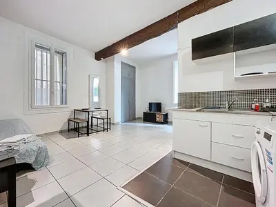 a kitchen with white cabinets and a table in it at Le Baudinet - Studio - Centre Ville - Rez-de-Chaussée in Narbonne