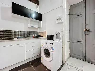 a white kitchen with a washing machine in it at Le Baudinet - Studio - Centre Ville - Rez-de-Chaussée in Narbonne