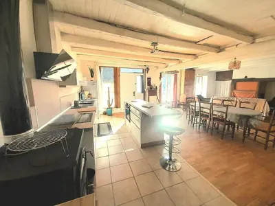 a kitchen and living room with a table and chairs at Maison entre mer et montagne in Cassagnolles