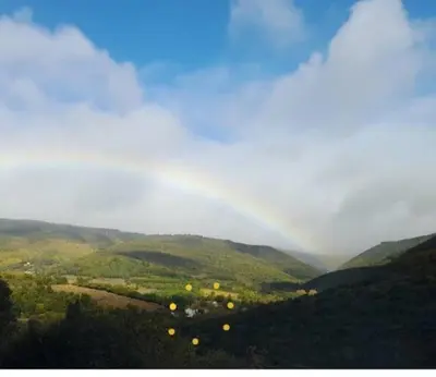 a rainbow in the sky over a green valley at Maison au pied de la Montagne Noire proche Carcassonne in Cassagnolles